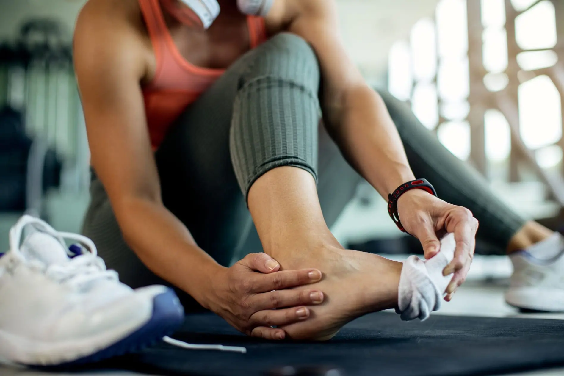 Close de uma mulher atlética que teve um entorse no pé durante um treino na academia