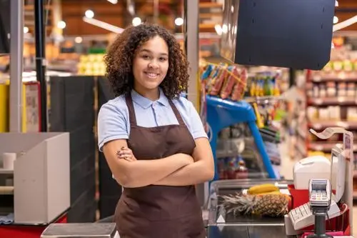 mulher sorrindo usando um avental durante o trabalho em um supermercado