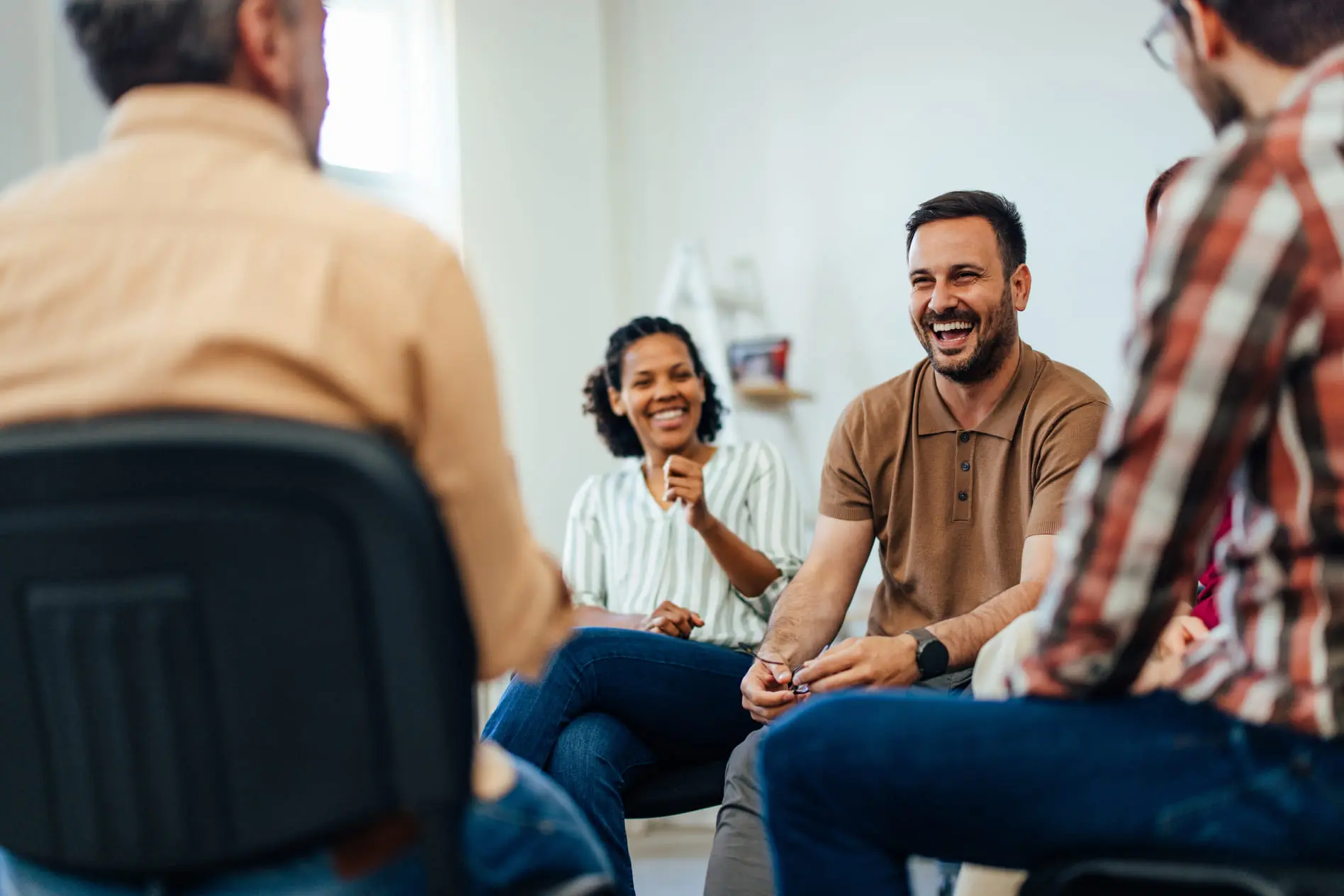 Um homem adulto, feliz, conversando com pessoas em uma terapia de grupo.